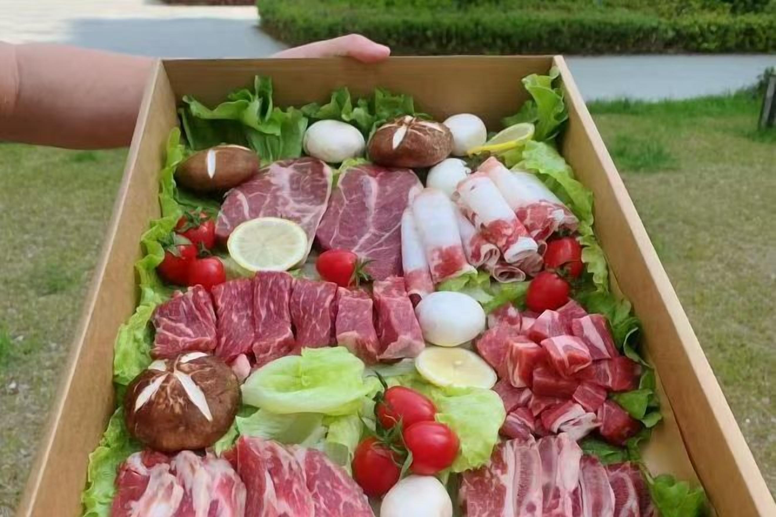 A wooden box filled with various meats, eggs, and vegetables.