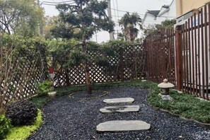 Un sendero de jardín con piedras para pisar, rodeado de follaje y una cerca decorativa.