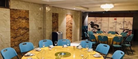 Un salón de conferencias con una mesa redonda, sillas azules y una araña.