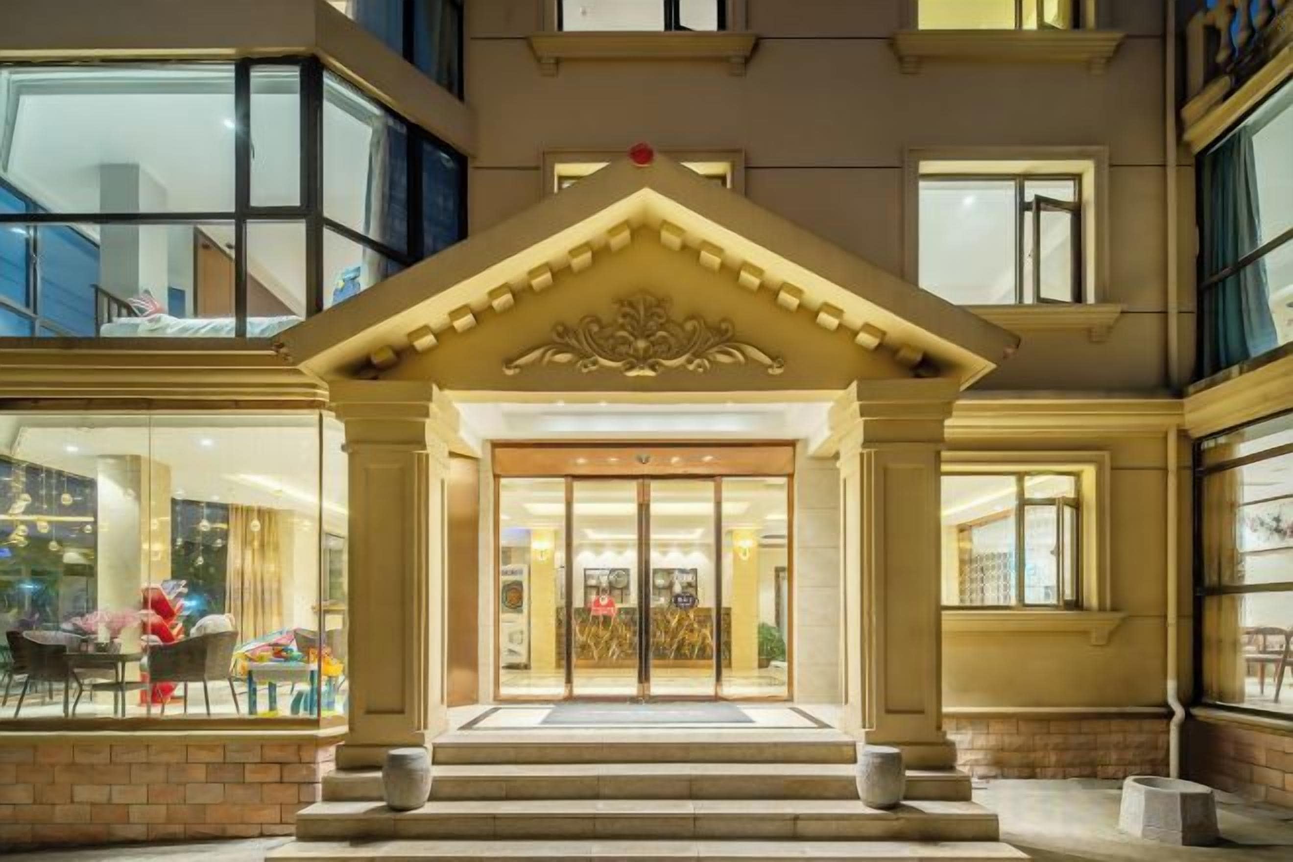Ein Hotel mit einem prunkvollen Bogen, einer Treppe, die davor führt, und einer großen Glasdoor.