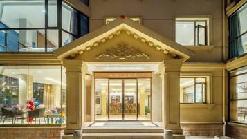 A hotel entrance with a grand archway, a set of steps leading up to it, and a large glass door.