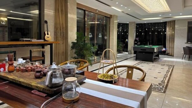 A modern hotel lobby with a pool table, a wooden table with pottery and a guitar, and a large window. - Qihupan Inn Heping (Wuxi)