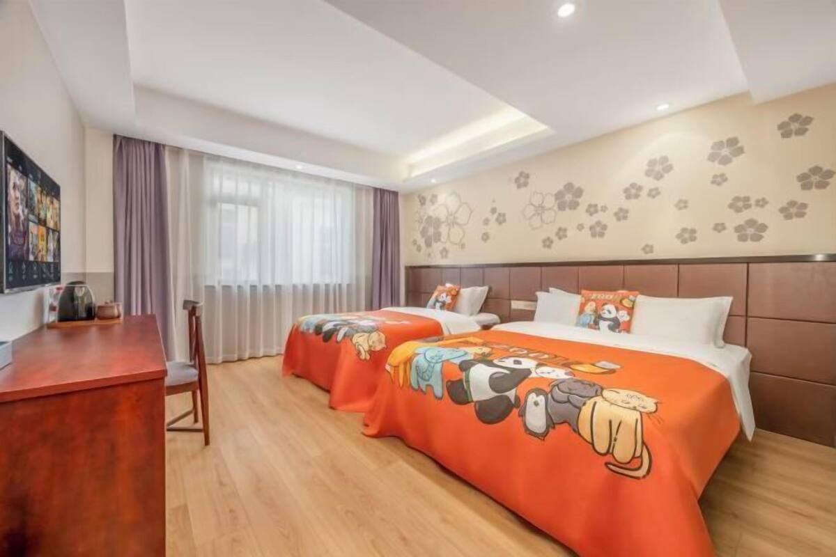Quarto de hotel com duas camas, uma escrivaninha e uma janela grande com cortinas.