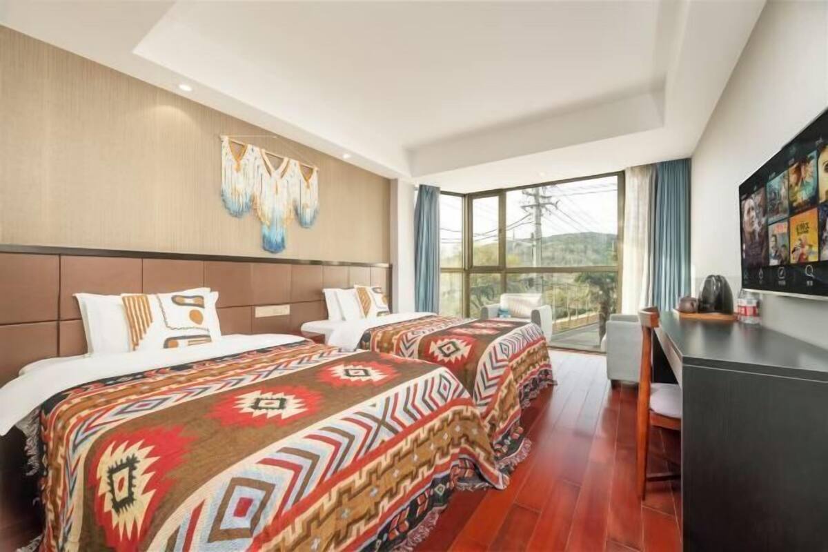 Quarto de hotel com uma cama grande, uma escrivaninha e vista para o exterior.