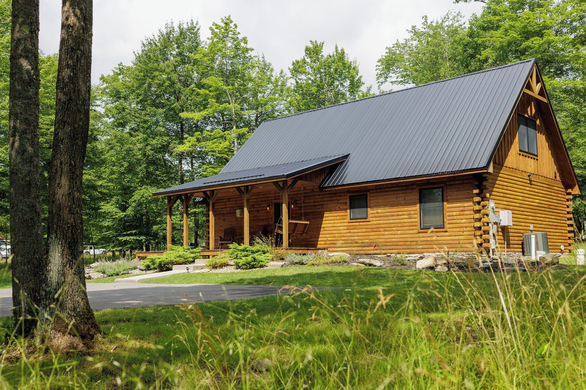 A log cabin with a sloped roof, wooden exterior, and a porch.