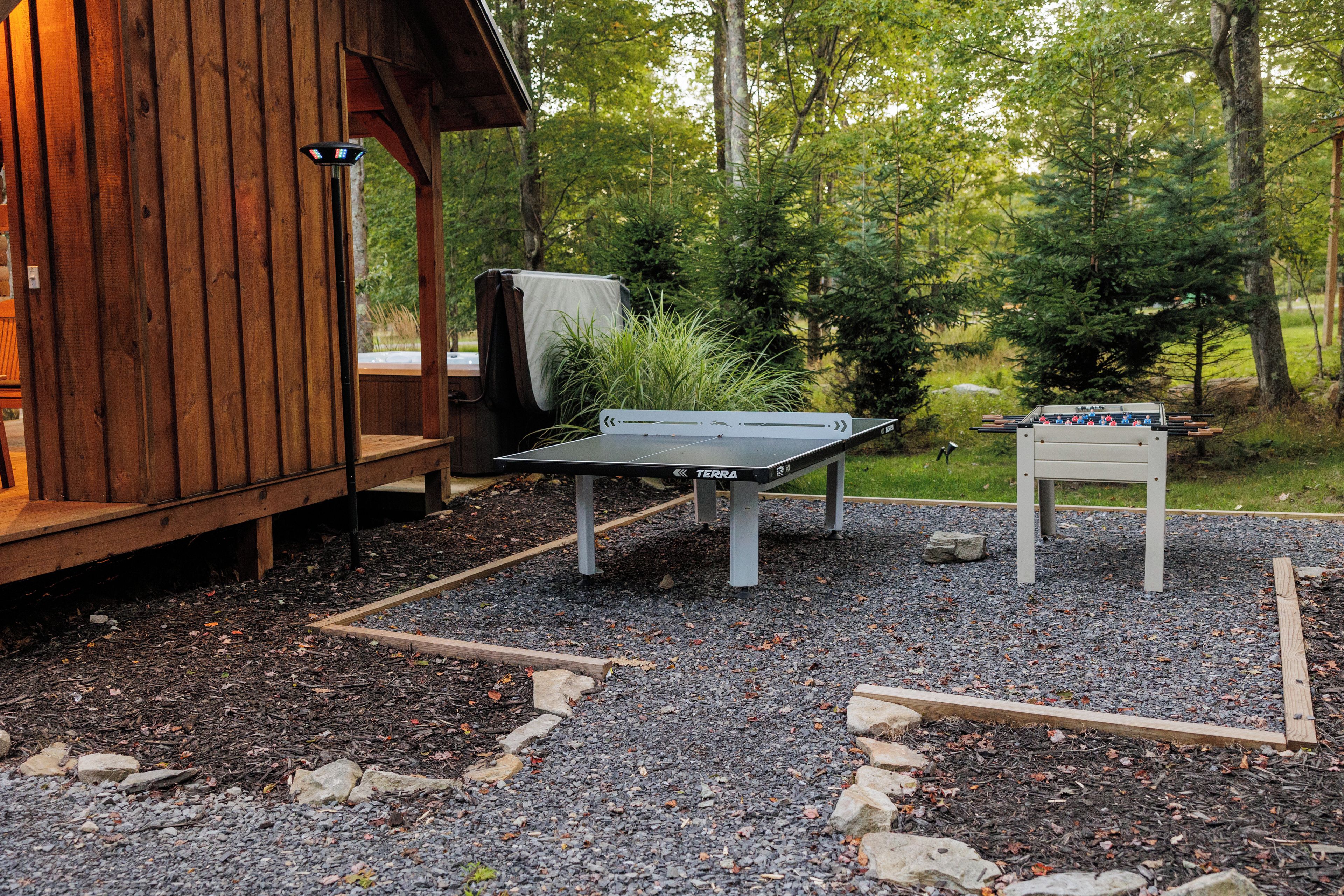 A wooden cabin with a foosball table and a covered seating area.