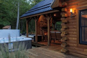 Een houten chalet met een hottub, buitenmeubels en een stenen open haard.