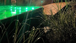 Une cabane en bois dotée d’une piscine, éclairée par des lampes extérieures.