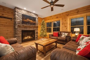 Una sala de estar acogedora con chimenea de piedra, sofás de cuero, una mesa de centro y un árbol de Navidad.