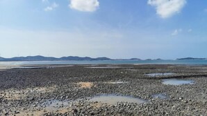 A rocky beach with water pools and distant mountains under a clear sky. - Lexiang. Smart Audio-Visual Boutique Stay (Changle International Airport) (Fuzhou)