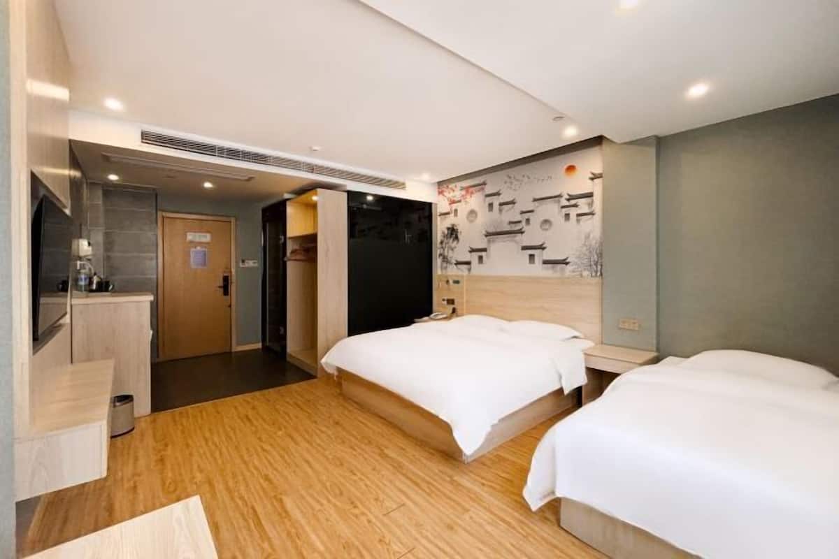 Habitación de hotel con dos camas, piso de madera, pared con arte abstracto, televisor y baño con espejo y lavamanos.