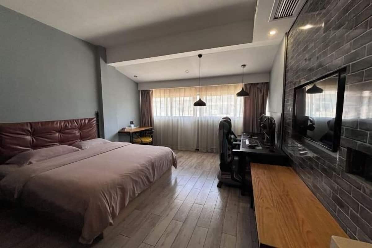 Un dormitorio con una cama grande, un escritorio de madera, un televisor y una chimenea.