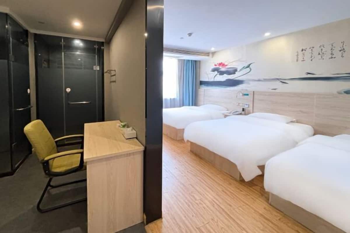 Habitación de hotel con escritorio, dos camas, una silla y un cuadro en la pared.