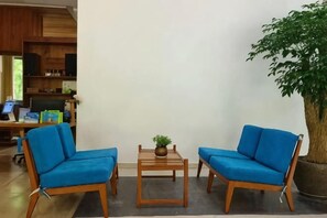 A room with two blue chairs, a small wooden table with a plant, and a large potted tree. - Bishan Banshe Holiday Villa (Xianju)