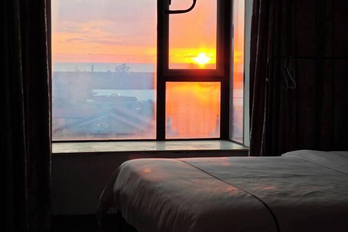 A room with a large window, a bed, and curtains.