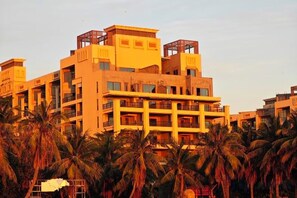 Un hotel de varios pisos con balcones, rodeado de palmeras.