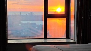 A room with a large window, a bed, and a view of a sunset over a body of water. - Qjia Ledong Xiangrui Seaview Business Hotel (Longmuwan Branch) (Ledong)