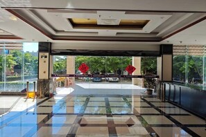 Un hall d’hôtel avec un sol carrelé, un comptoir d’accueil et une vue sur l’extérieur.