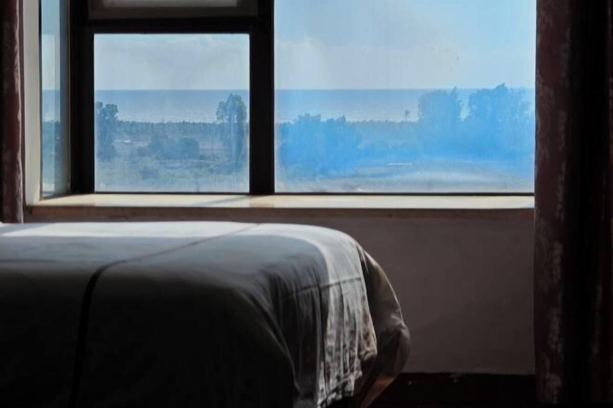 A room with a bed and a window overlooking a landscape.