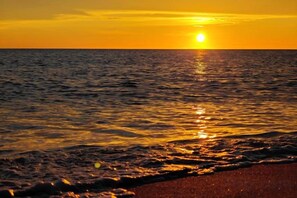 A sunset over a body of water with waves approaching the shore. - Qjia Ledong Xiangrui Seaview Business Hotel (Longmuwan Branch) (Ledong)