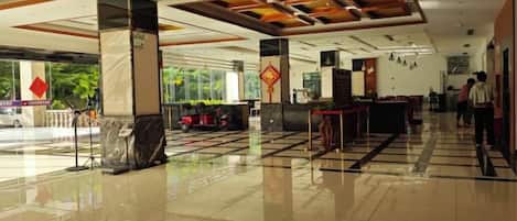 A hotel lobby with a check-in counter, seating area, and a large window offering a view of the outside.