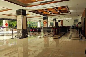 A hotel lobby with a check-in counter, seating area, and a large window offering a view of the outside. - Qjia Ledong Xiangrui Seaview Business Hotel (Longmuwan Branch) (Ledong)
