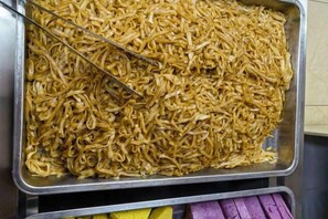 Una bandeja metálica grande llena de fideos cocidos.