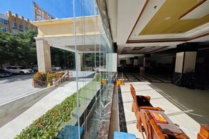 Un vestíbulo de hotel con separador de vidrio, asientos exteriores y vista a la calle.