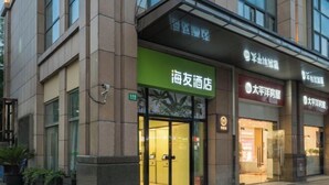 Um hotel com uma placa verde para o "海友酒店" e uma placa vermelha para o "大海洋酒店".