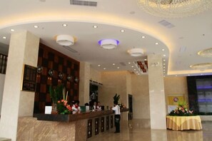 Um saguão de hotel com uma mesa de recepção, um relógio e um teto decorativo.