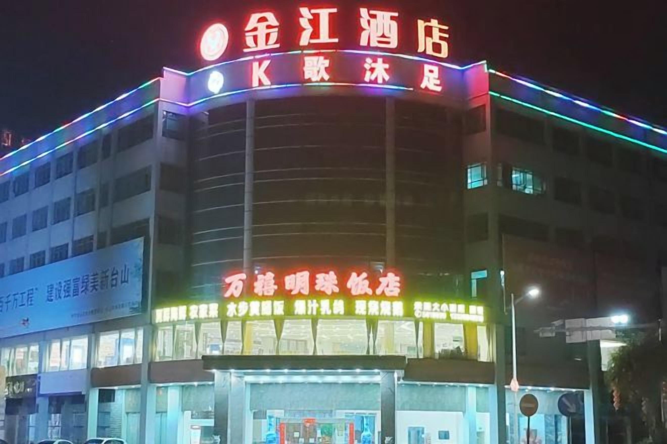A hotel with a prominent sign, multiple floors, and illuminated signage.