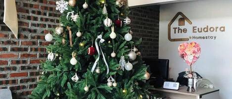 A Christmas tree with ornaments and presents, a reception desk, and a brick wall.