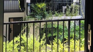 Un balcon orné de plantes suspendues, d’où l’on peut admirer un immeuble doté de nombreux balcons.