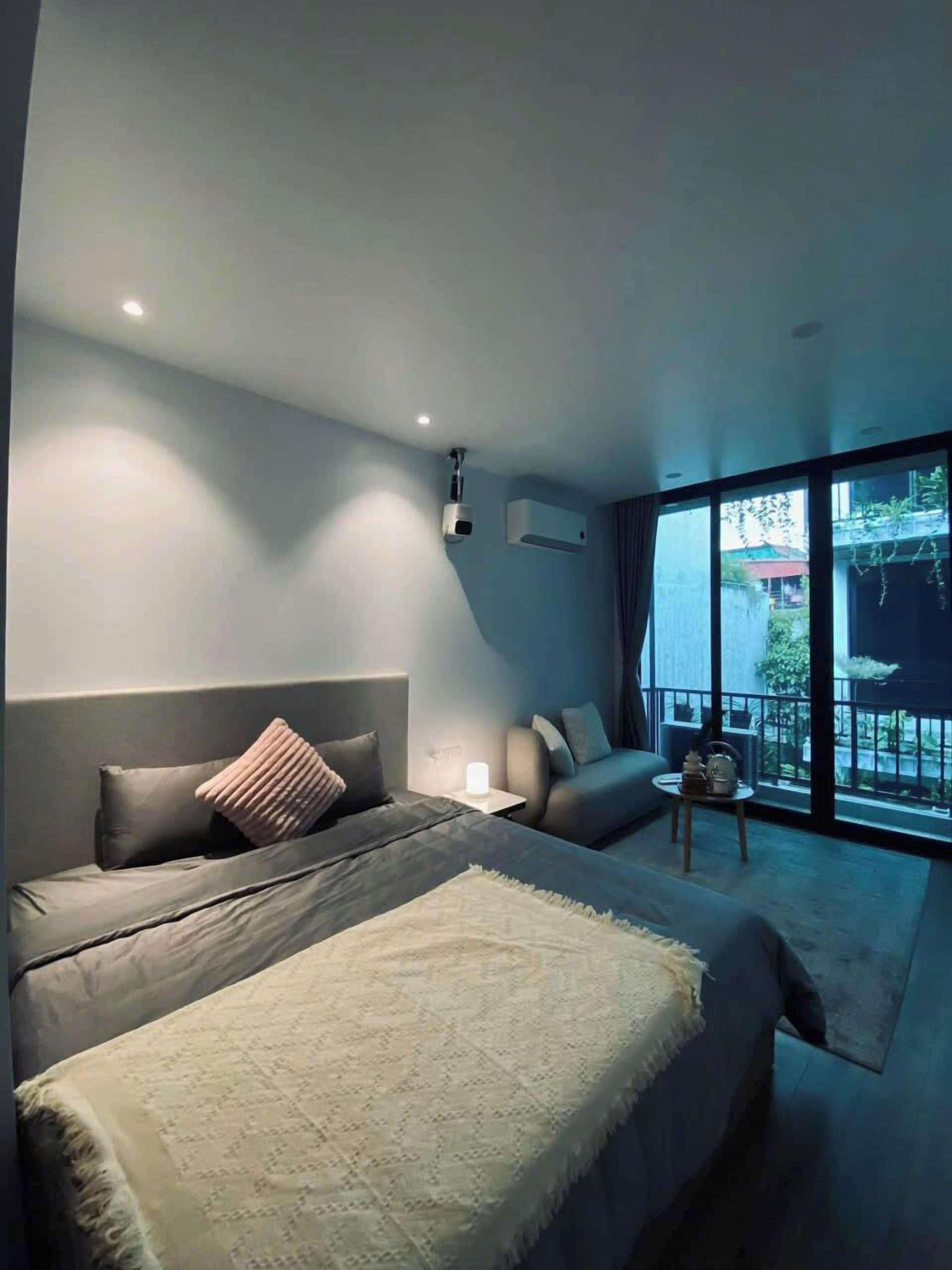Un dormitorio moderno con una cama grande, un sofá, una mesita y un balcón con vistas.