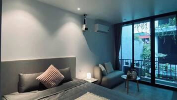 Un dormitorio moderno con una cama grande, un sofá, una mesita y un balcón con vistas.