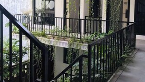 Un bâtiment moderne doté d’un escalier, de balcons et de plantes suspendues.