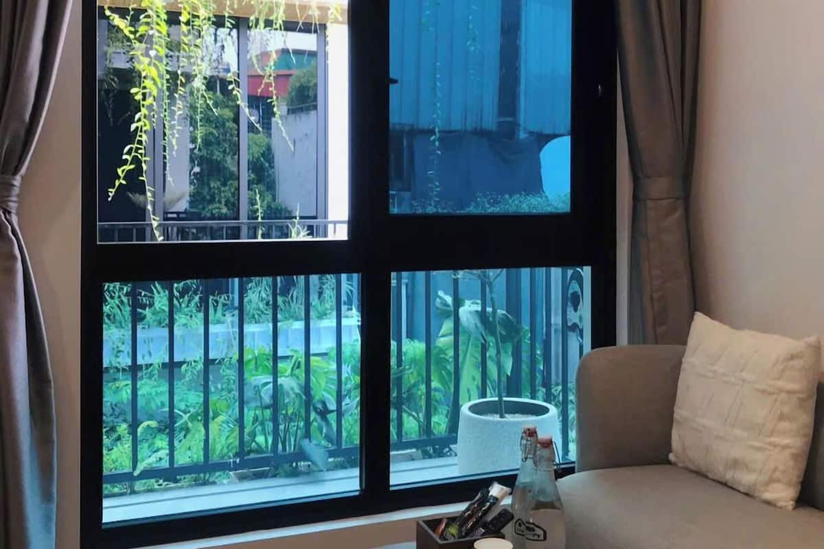 A room with a large window, a sofa, and a small table with items on it.