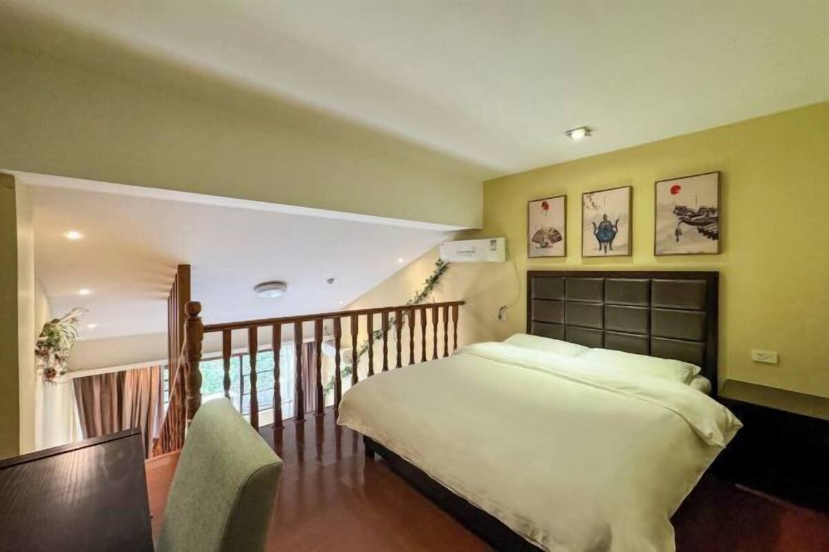 A hotel room with a bed, a balcony, and artwork on the wall.