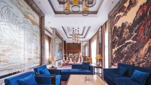 A spacious lobby with blue sofas, a wooden coffee table, and large wall murals. - Dragon Tiger Villa (Guixi)