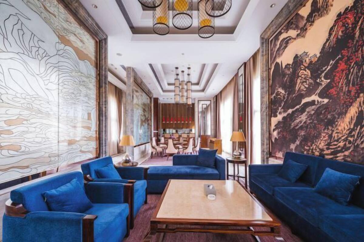 A spacious lobby with blue sofas, a wooden coffee table, and large wall murals.