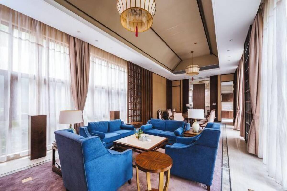 A spacious hotel lobby with a blue sofa set, a round coffee table, and a chandelier.