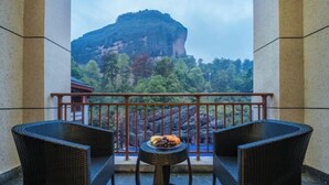 A balcony with wicker furniture, a small table with fruit, and a view of a mountain. - Dragon Tiger Villa (Guixi)