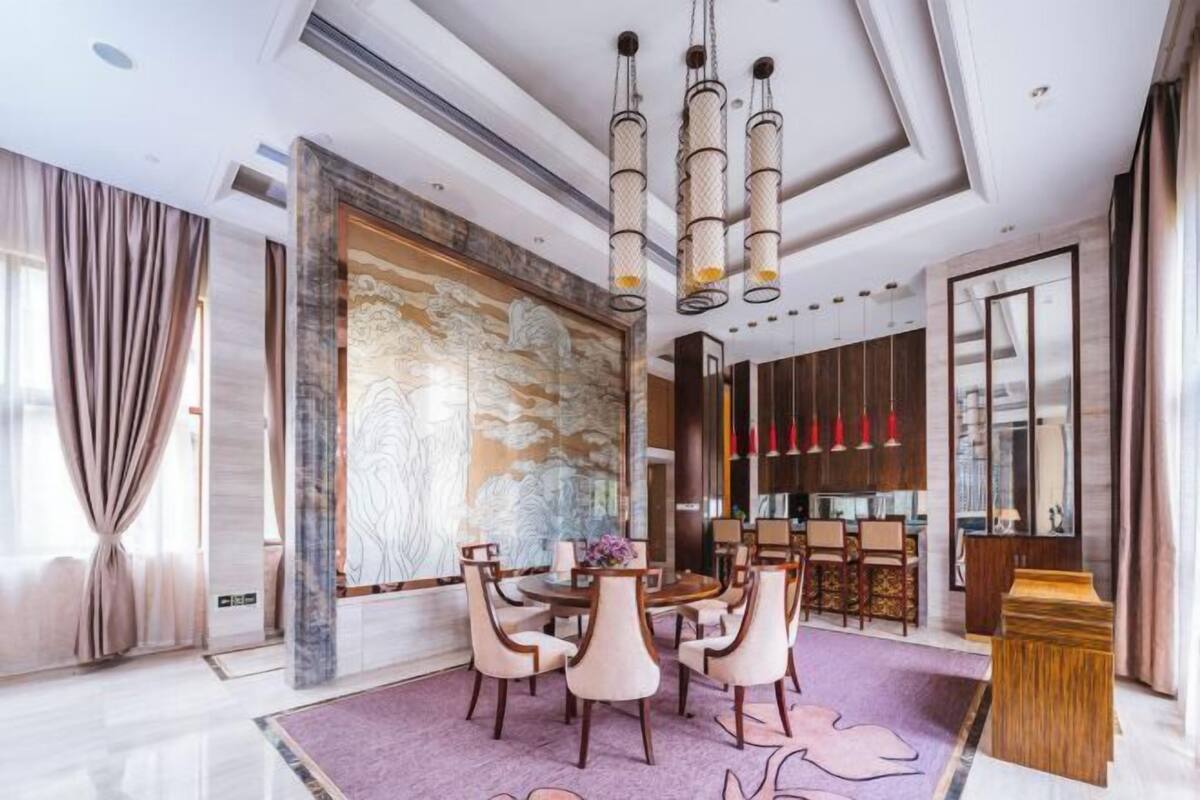 A modern dining area with a round table, chairs, and a large abstract wall art piece.
