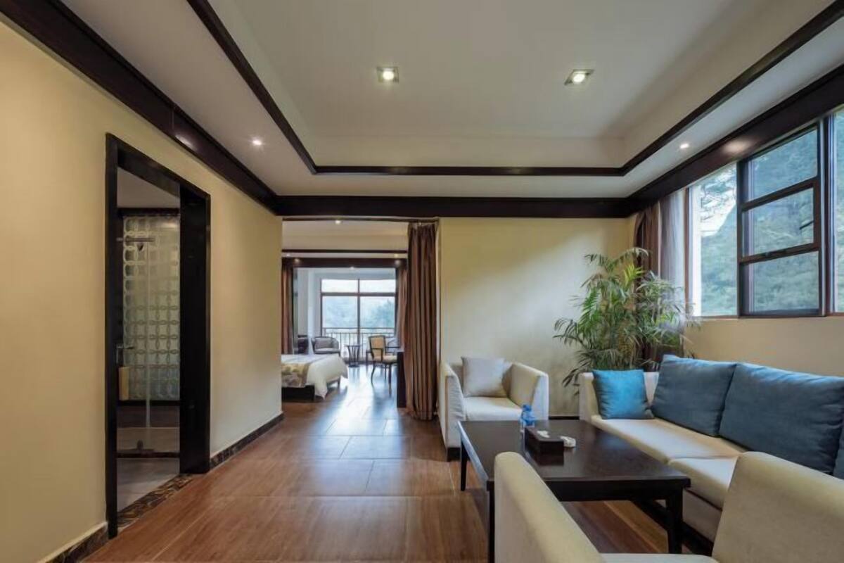 A hotel room with a wooden floor, a sofa, a table, and a potted plant.