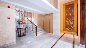 A modern hotel lobby with a marble floor, a staircase, and a decorative wall. - Dragon Tiger Villa (Guixi)
