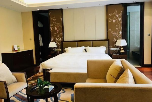 A hotel room with a large bed, two bedside tables with lamps, a sofa, and a small coffee table. - Dragon Tiger Villa (Guixi)