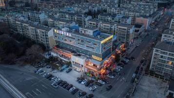 A multi-story building with a parking lot in front, surrounded by other buildings.