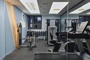 Une salle de sport équipée de matériel d’exercice, d’un miroir et d’une fenêtre.