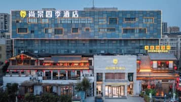 A hotel with a modern facade, a traditional entrance, and a parking area.