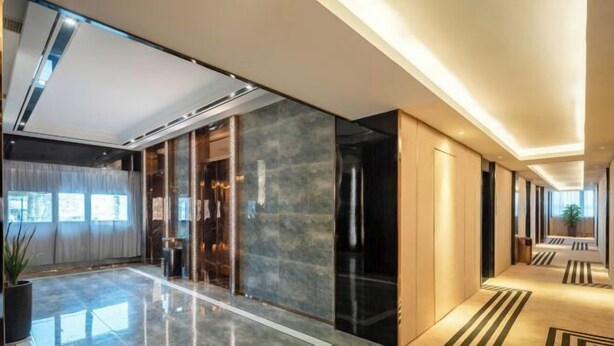 A modern hotel lobby with a polished marble floor, a glass elevator, and a long corridor with patterned carpet. - Shangjing Full Seasons Hotel (Xuzhou)